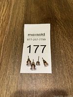 Four gold-tone stud earrings beside lot tag
