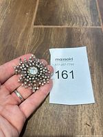 Brooch front view in hand with lot tag