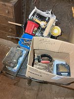 Mixed tools on small table: socket cases, air sprayer, painting tray, roller, box of wrenches