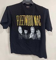 Front of black Fleetwood Mac T-shirt showing yellow text and band member portraits