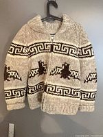 Front view of cream and brown wool Cowichan style zip-up cardigan on hanger