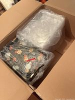 overview of open shipping box showing stacked trays and lids in plastic bags