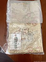 Obi folded inside clear plastic packaging showing gold and ivory embroidered side