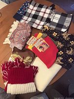 Overview of all scarves and packaged neck warmers on table