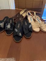 All four pairs on table: brown loafers, two black slide sandal pairs, beige wedge sandals