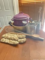 Group view showing pot with lid, steamer baskets, whisk, spoon, oven mitts, thermometer