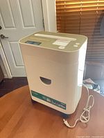 Full view of shredder on table showing body, top, casters and power cord
