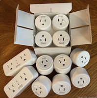 Open 4-pack box showing four round plugs, six additional loose round plugs and two dual-outlet plugs