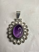Front view of silver-plated pendant with purple amethyst stone and filigree frame