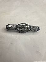 Full view of silver-tone filigree rhinestone bar brooch front