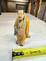 Front view of ceramic figurine showing full design and measuring tape indicating height