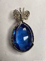 Front view of pendant showing blue faceted glass and butterfly bail