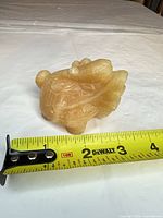 Side view of yellow stone turtle with tape measure showing approx 4 in