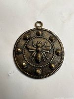 front view of pendant showing bee relief and stud accents
