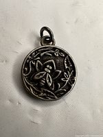 Front view of sterling silver pendant showing bee and floral relief