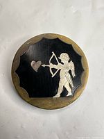 Front view of round brooch showing Cupid silhouette and heart