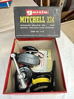 Open box showing Garcia Mitchell 324 reel, spare spool, paperwork