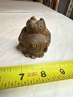 Front view of hand-carved wooden figurine with measuring tape showing height under 4 inches