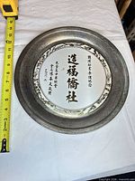 Full view of round silver-plated tray with measuring tape showing diameter