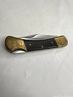 Closed knife showing wood handle and brass bolsters