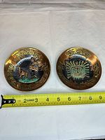 Both copper plates side by side with measuring tape for scale