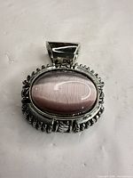 Front view of pendant showing pink cat's eye cabochon and decorative frame