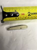 Knife next to measuring tape showing 2 in closed length