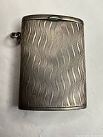 Front view of silver vesta case showing wavy guilloche pattern and suspension ring