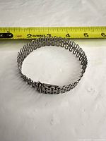 Bracelet laid in circle beside measuring tape showing size