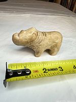 Side view of soapstone animal with measuring tape indicating ~3 inch length