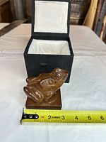 Frog figurine beside tape measure in open presentation box