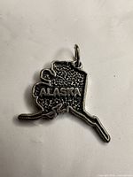 Front view showing Alaska outline, lettering and jump ring