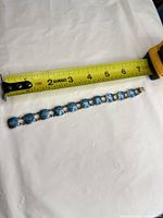 Bracelet next to tape measure showing about 7 inch length