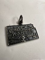 Front view showing Kansas outline, city names, landmarks, oxidized background, jump ring