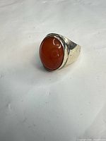 Front view showing oval orange cabochon and silver bezel