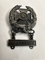 Front view of sterling silver shooting badge with laurel wreath, cross, and SMALL BORE RIFLE bar