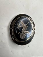 Front view of oval niello brooch with Thai dancer motif
