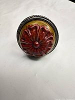 Front view of ring showing carved red flower on olive-yellow background within rope-edge bezel
