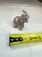 Front view of carved stone elephant with measuring tape for scale