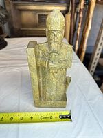 Full front view showing warrior figure, helmet, sword, and rectangular side support with tape measure indicating about 8 inches