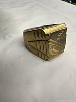 Side view of brass ring showing geometric engraved bezel and patina