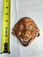 Front view with tape measure showing approx. 4 in height, rusted face bottle opener