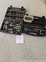 Open black case displaying sockets, ratchet and accessories with separate tub of bolts