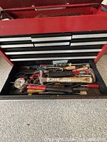 Open drawer showing multiple hammers, pliers, screwdrivers and hardware