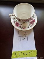 Teacup nested on saucer showing pattern and size note