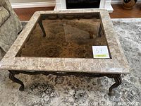 Full view of square coffee table showing faux stone top, glass inset and metal legs