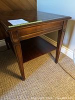 Three-quarter view of dark brown veneer end table showing top, apron, legs, and lower shelf