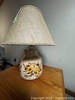 Lamp front view showing ceramic floral base and burlap shade