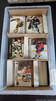 Top view of plastic bin containing stacks of hockey trading cards with labeled dividers for Fleer, Parkhurst, Pro Set, Atomic