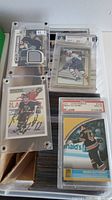 Four individual hockey cards in hard cases on top of large stack; shows memorabilia patch, Beckett graded, autographed and PSA graded examples